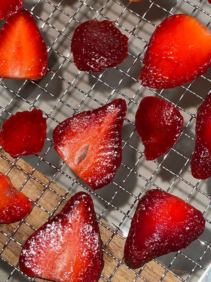 services-01 Vibrant slices of red strawberries placed on a wire rack, showcasing freshness and texture.